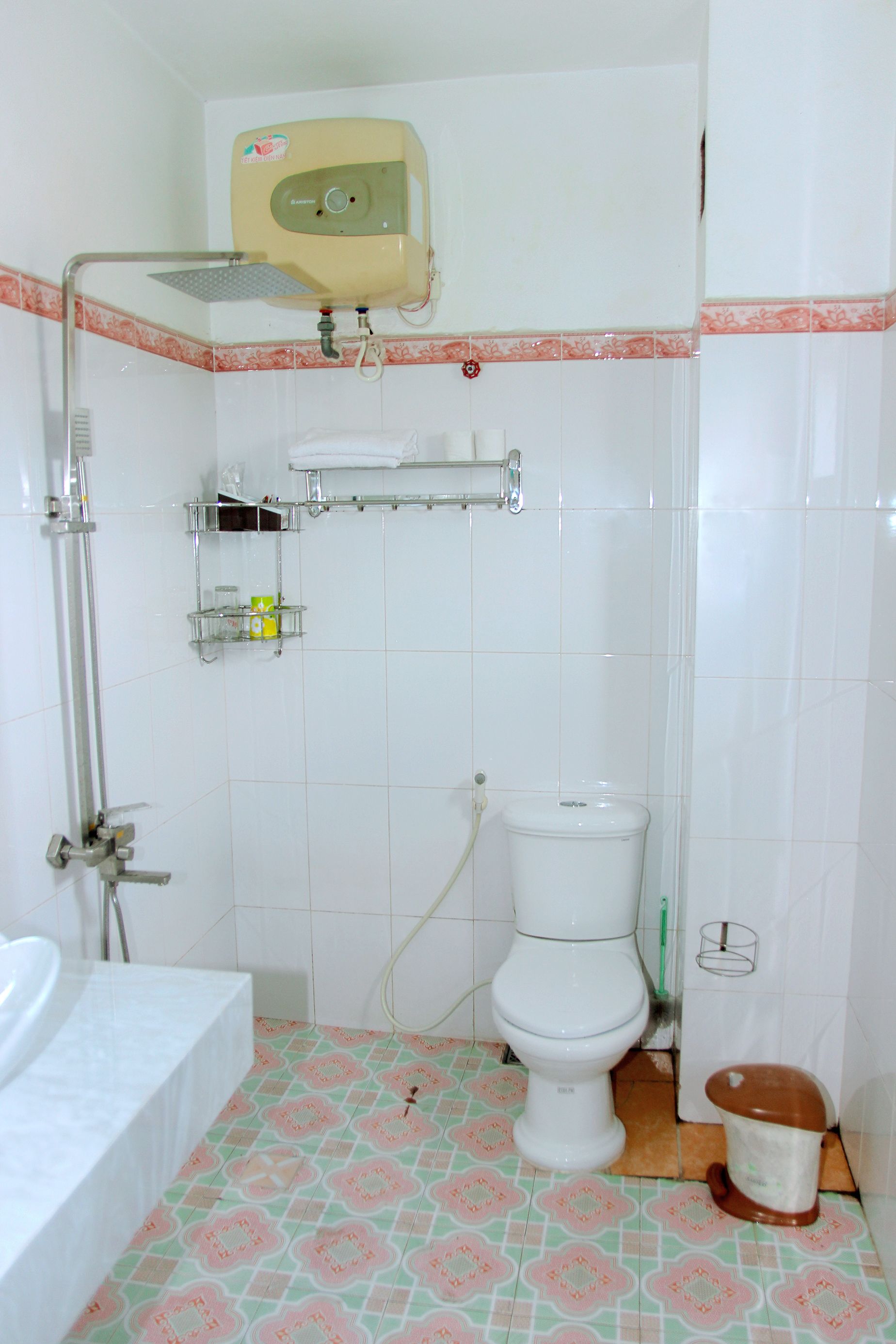 A bathroom with a toilet, sink, shower, and a toilet paper holder.