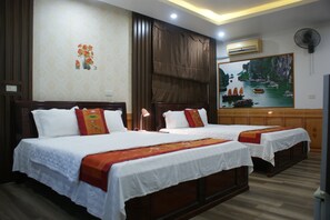 A hotel room with two beds, a painting of boats on the wall, and a fan on the ceiling. - Xuan Hoa Hotel (Hoa Lu)