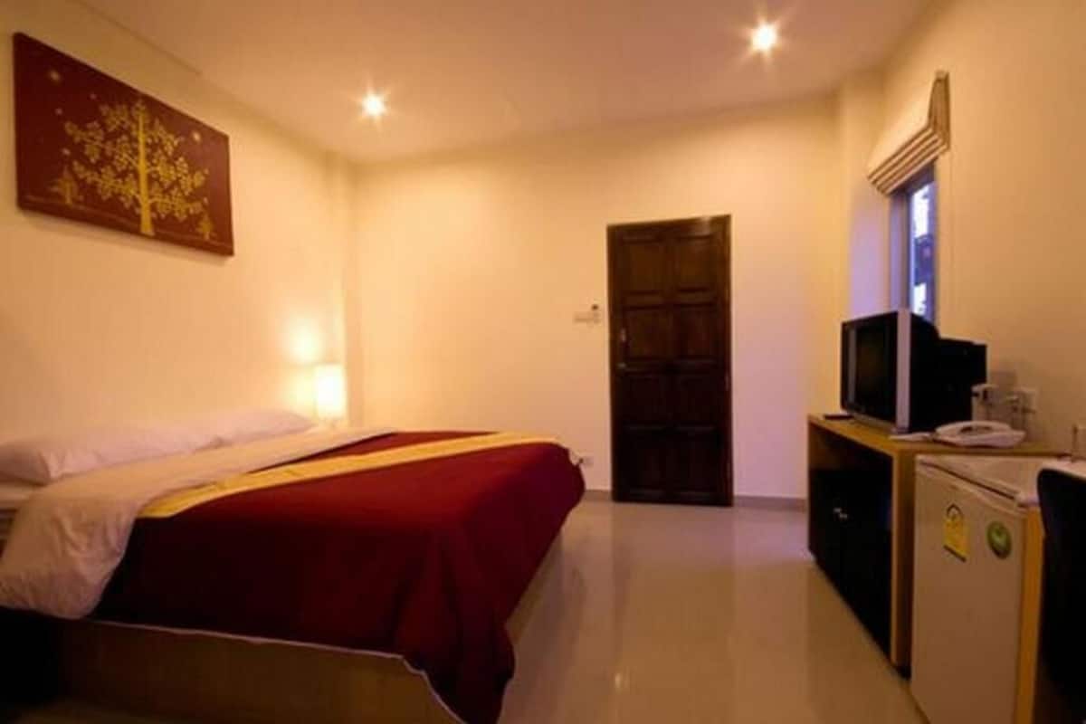 A hotel room with a bed, a desk with a computer, a television, and a door.