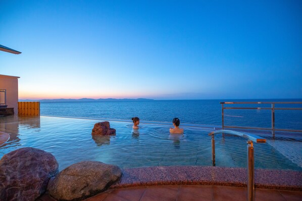 An infinity pool with a view of the sea at dusk.