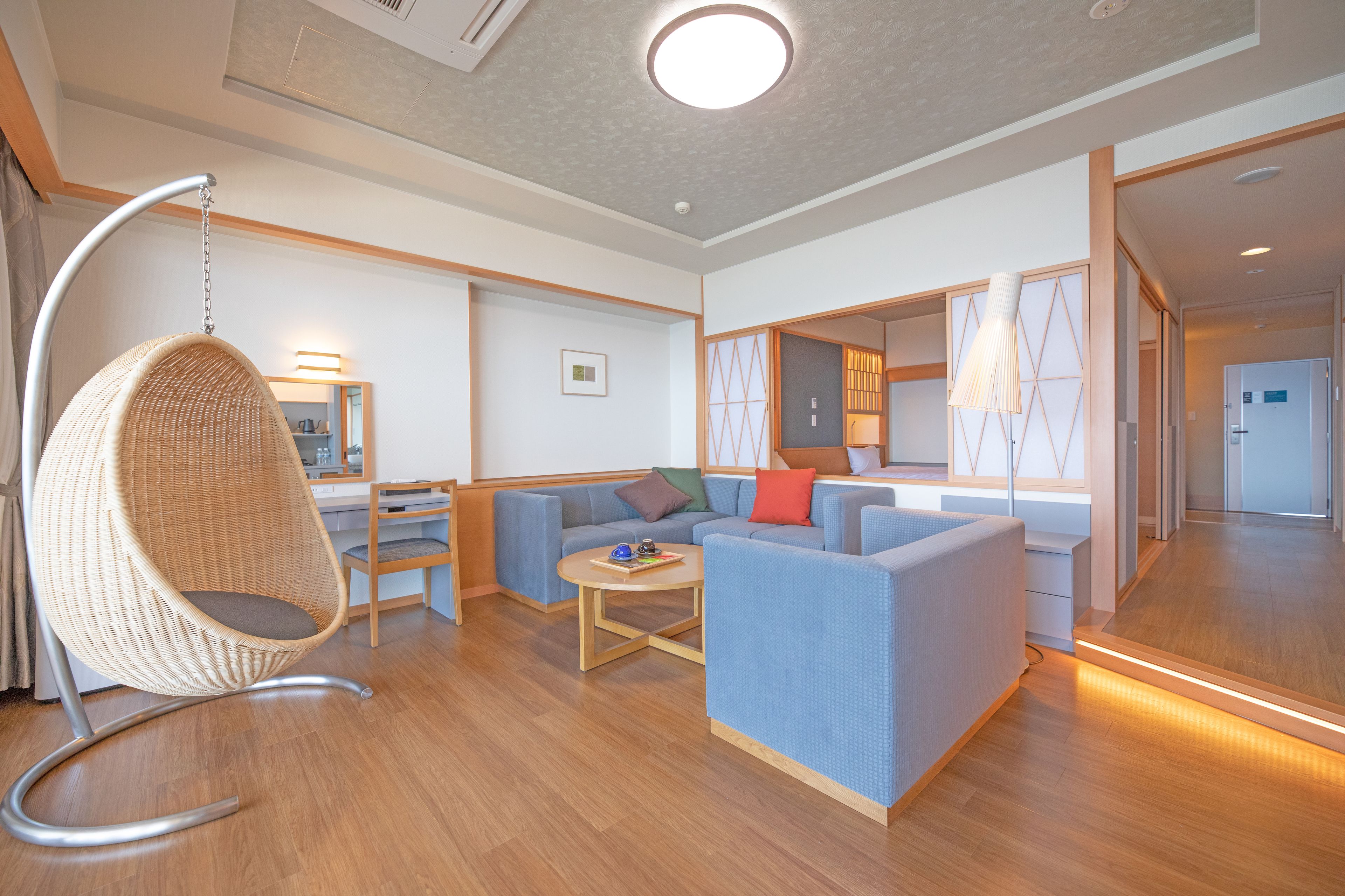 A modern living room with a hanging chair, sofas, and a coffee table.