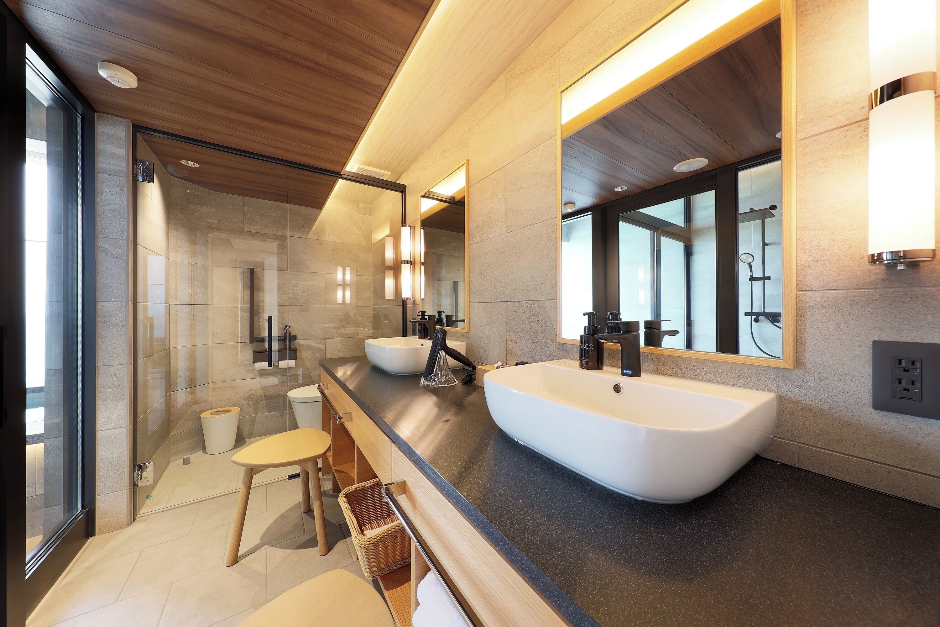 A modern bathroom with a large freestanding bathtub, a double sink, and a glass-enclosed shower area.