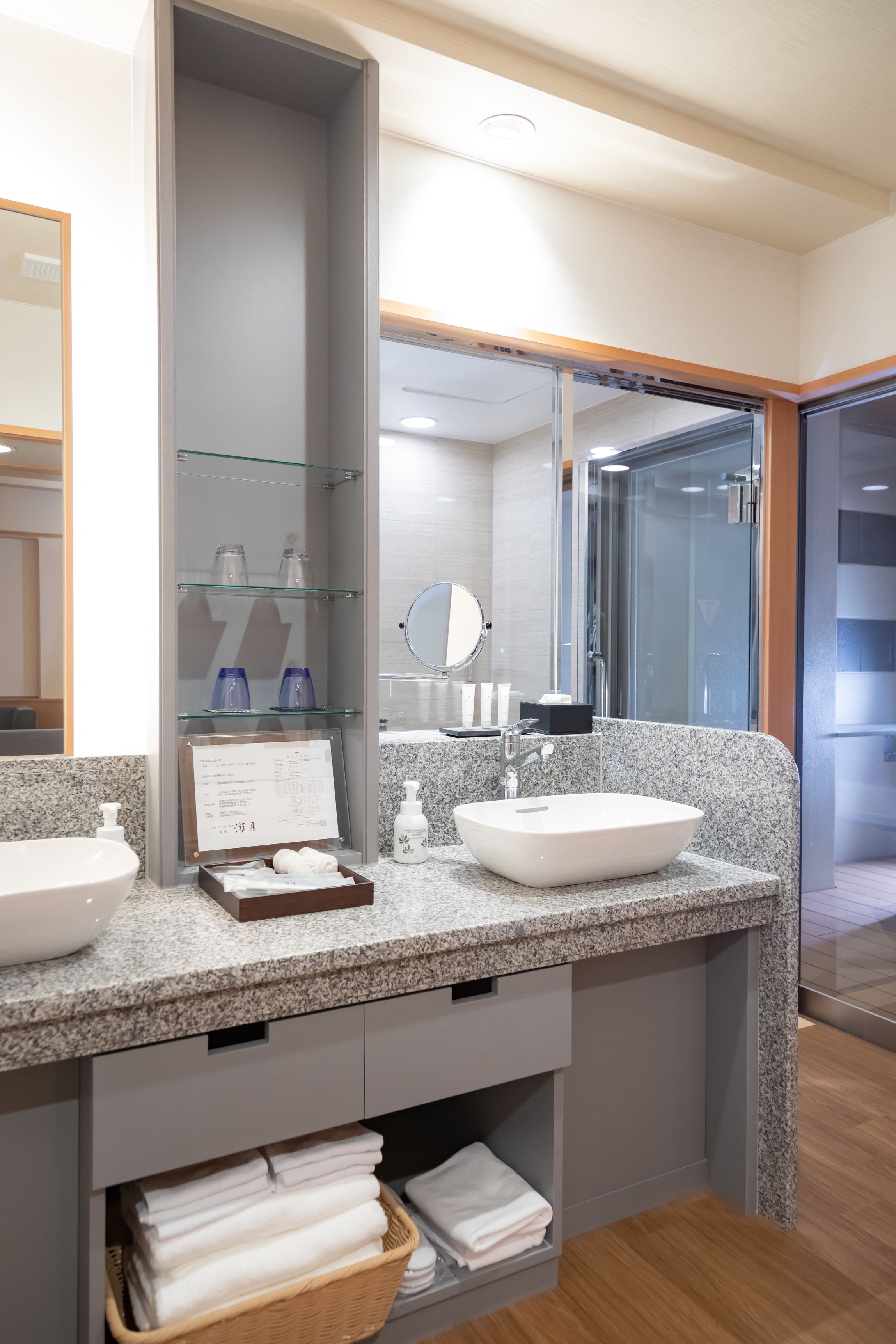 A modern bathroom with two sinks, a large mirror, and a glass shower enclosure.