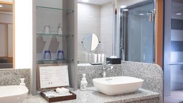A modern bathroom with two sinks, a large mirror, and a glass shower enclosure.