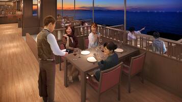 Un restaurant avec vue sur la mer, doté d’un plancher en bois et d’un espace bar.