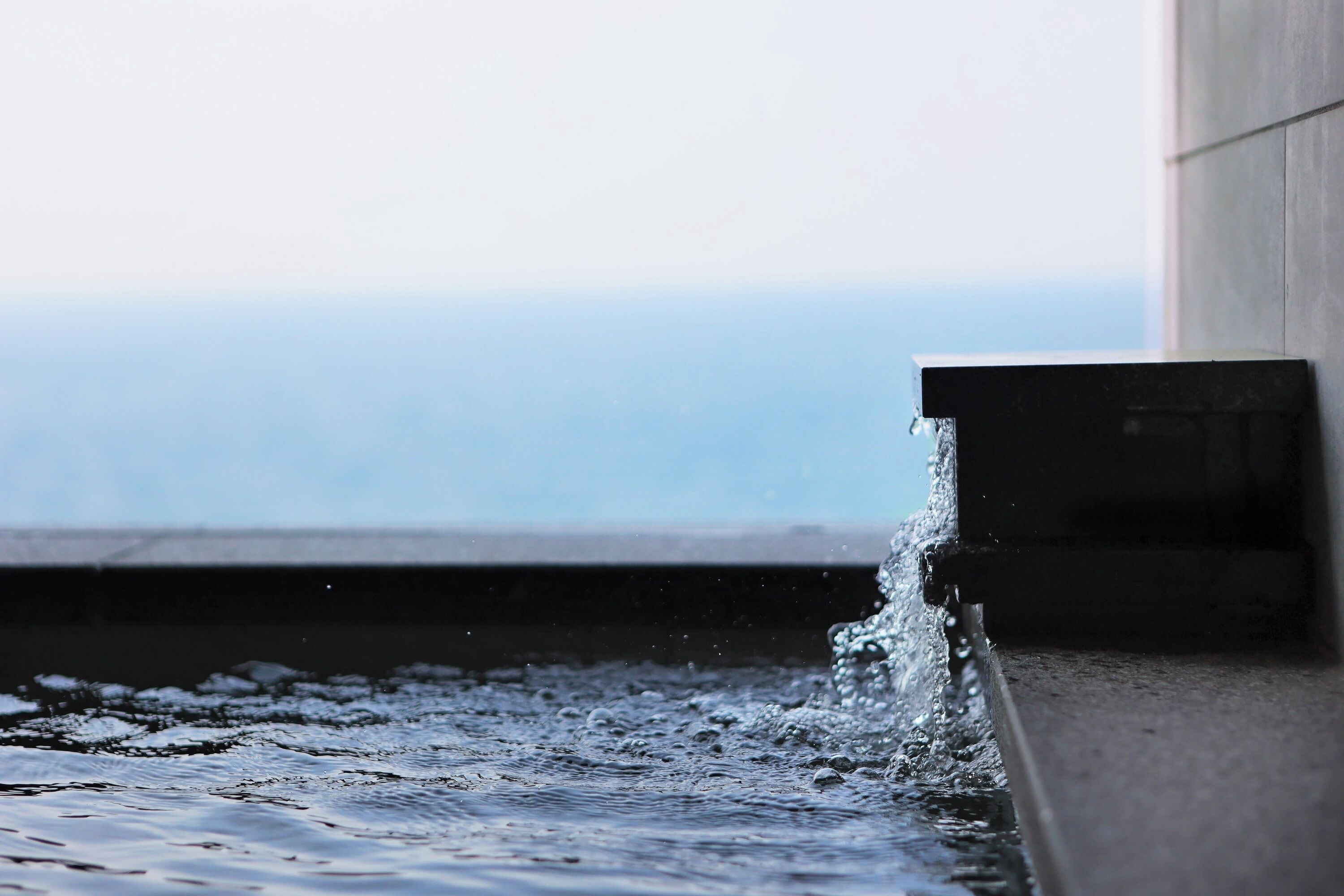 A water feature with a concrete structure and a view of the ocean.