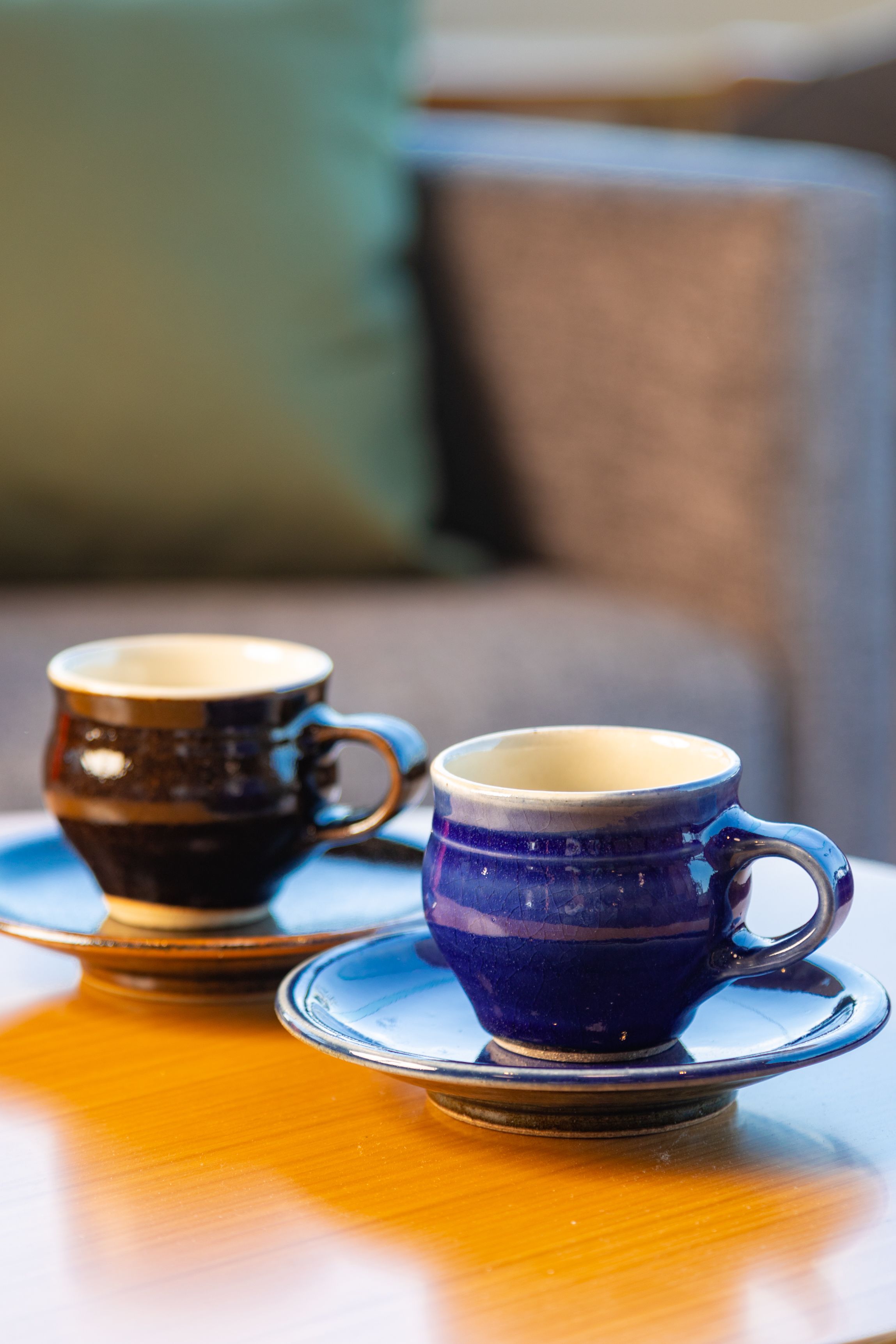 Two ceramic cups on a saucer on a wooden table.