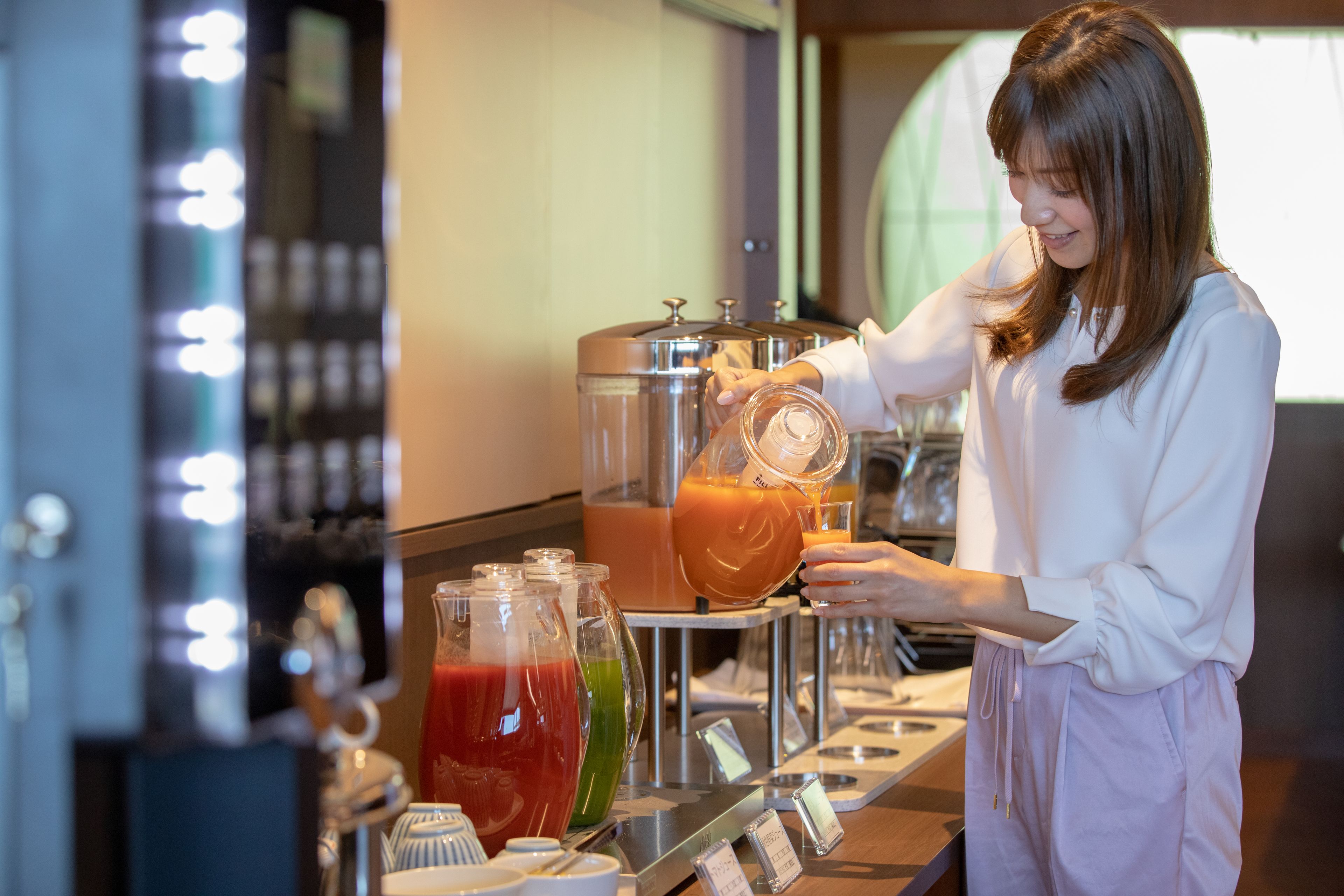 A person pouring a drink from a pitcher into a glass.