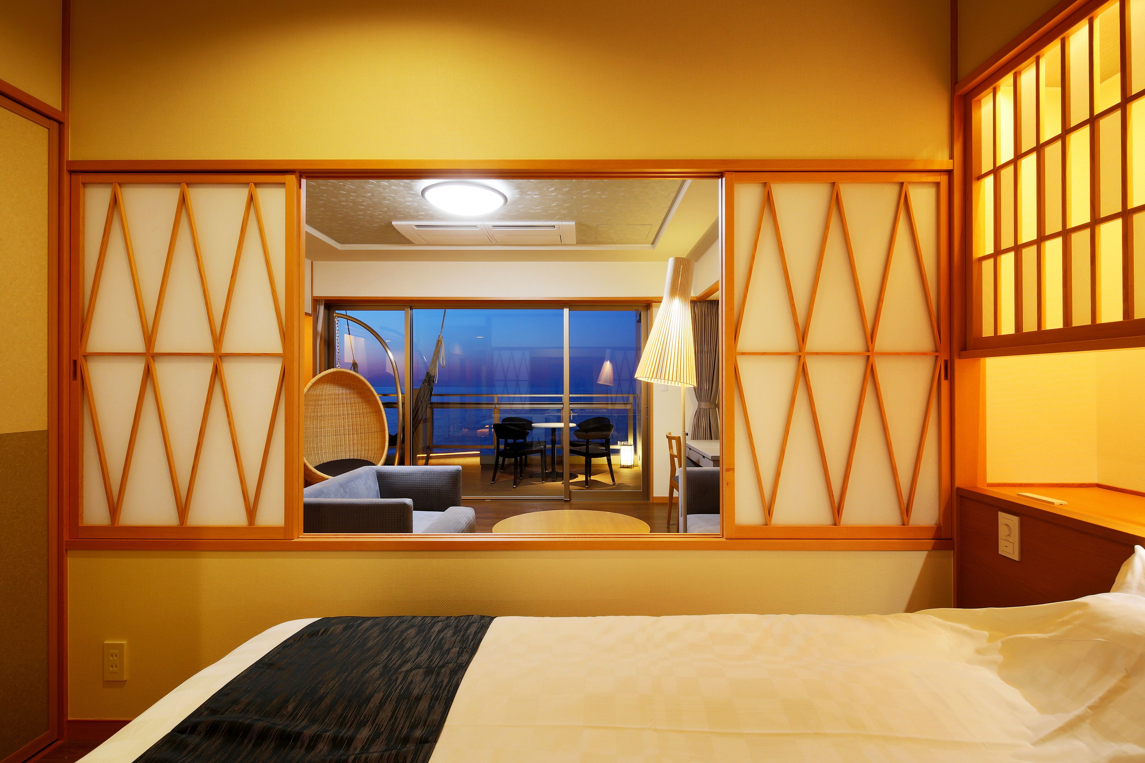 Habitación de hotel con cama, escritorio y vistas a un balcón con asientos.