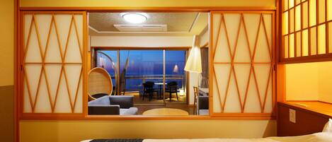 Habitación de hotel con cama, escritorio y vistas a un balcón con asientos.