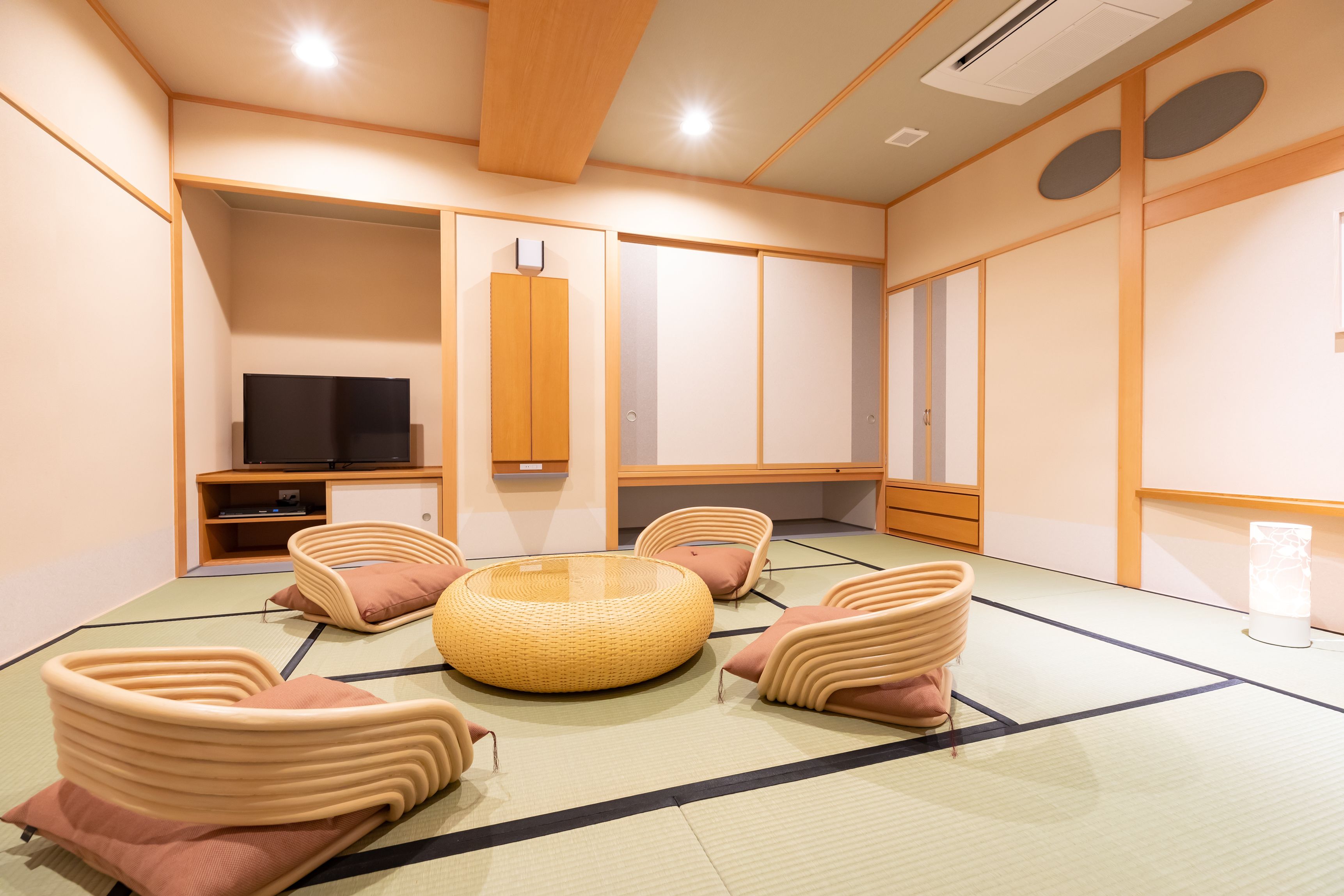 A tatami mat room with a television, cushioned seating, and traditional Japanese decor.
