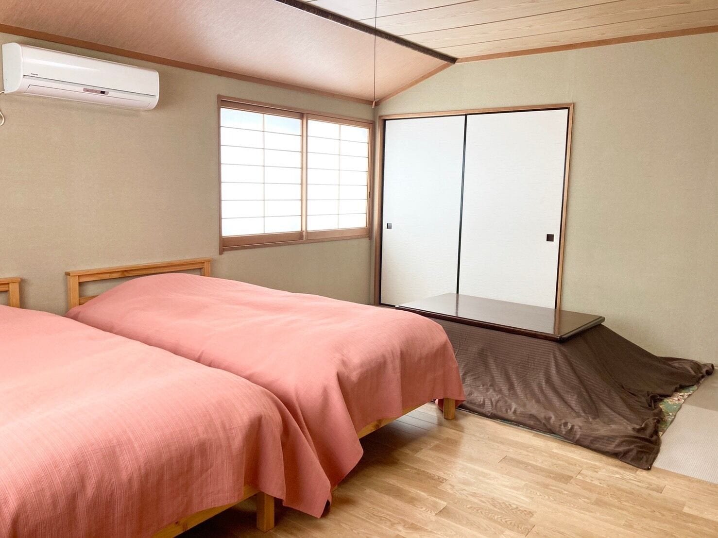 A bedroom with two beds, a wardrobe, and an air conditioning unit.
