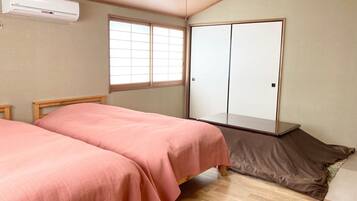 A bedroom with two beds, a wardrobe, and an air conditioning unit.