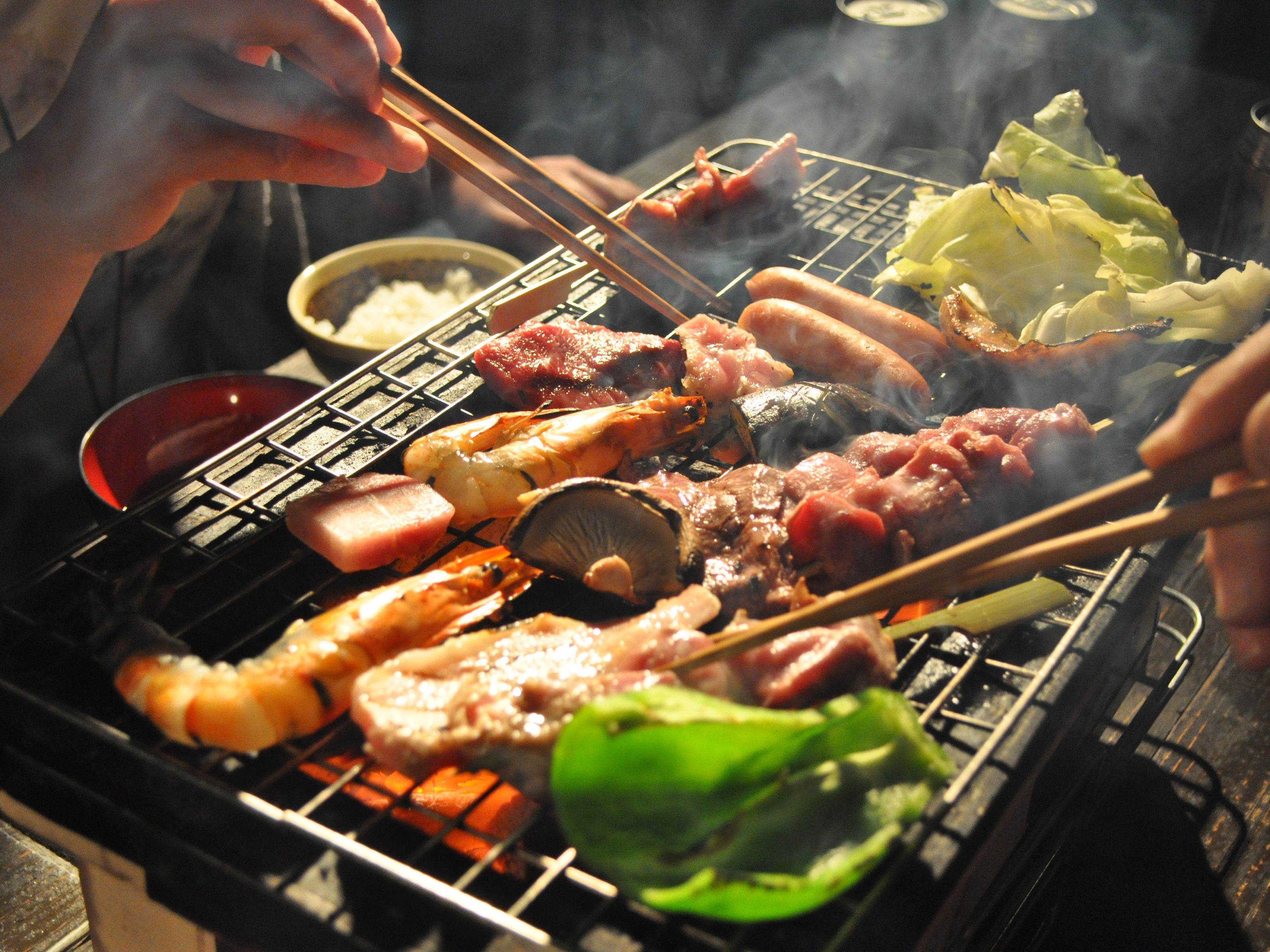 Una variedad de carnes a la parrilla y verduras sobre una barbacoa.