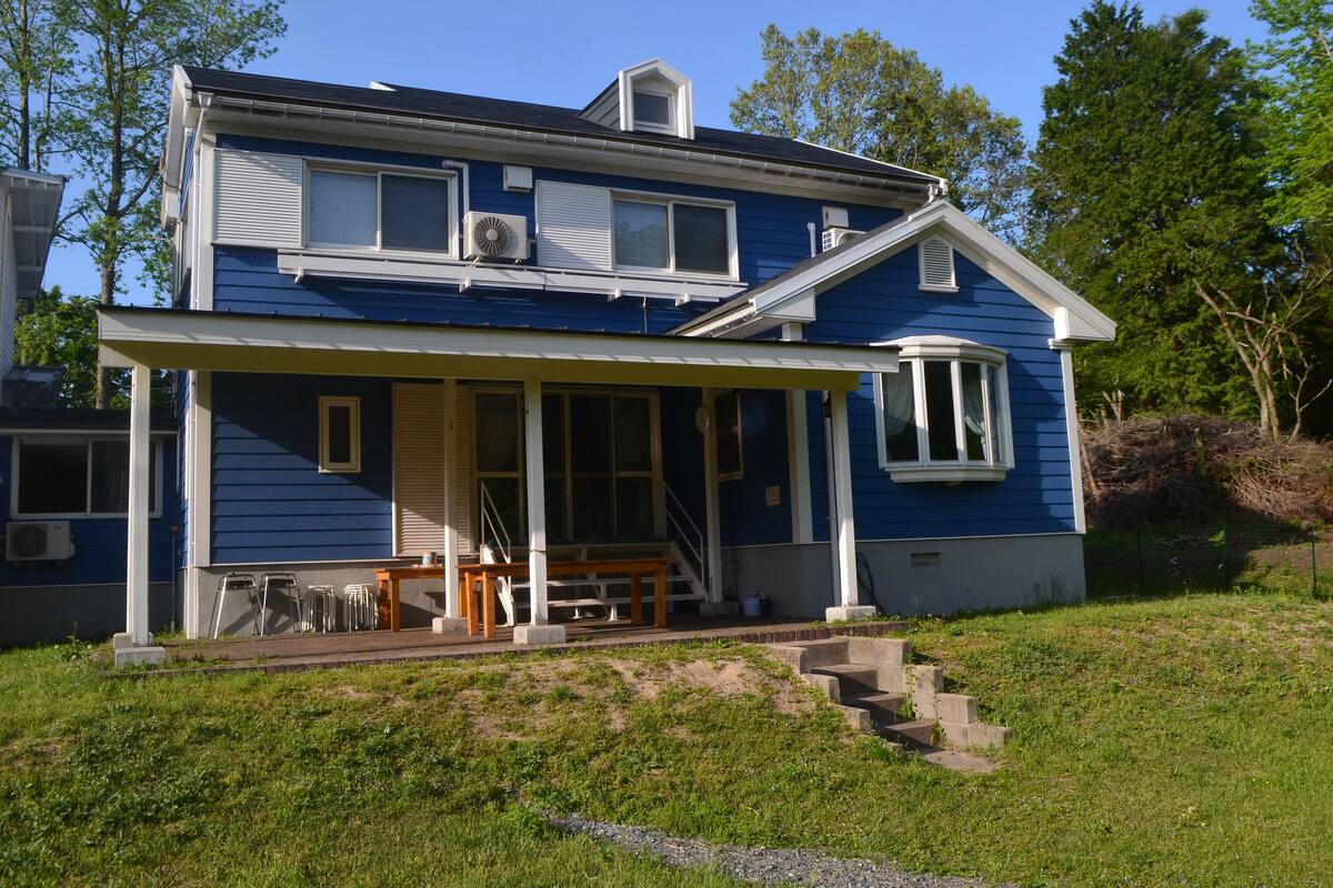 A two-story house with a covered porch and a small staircase leading to the entrance.