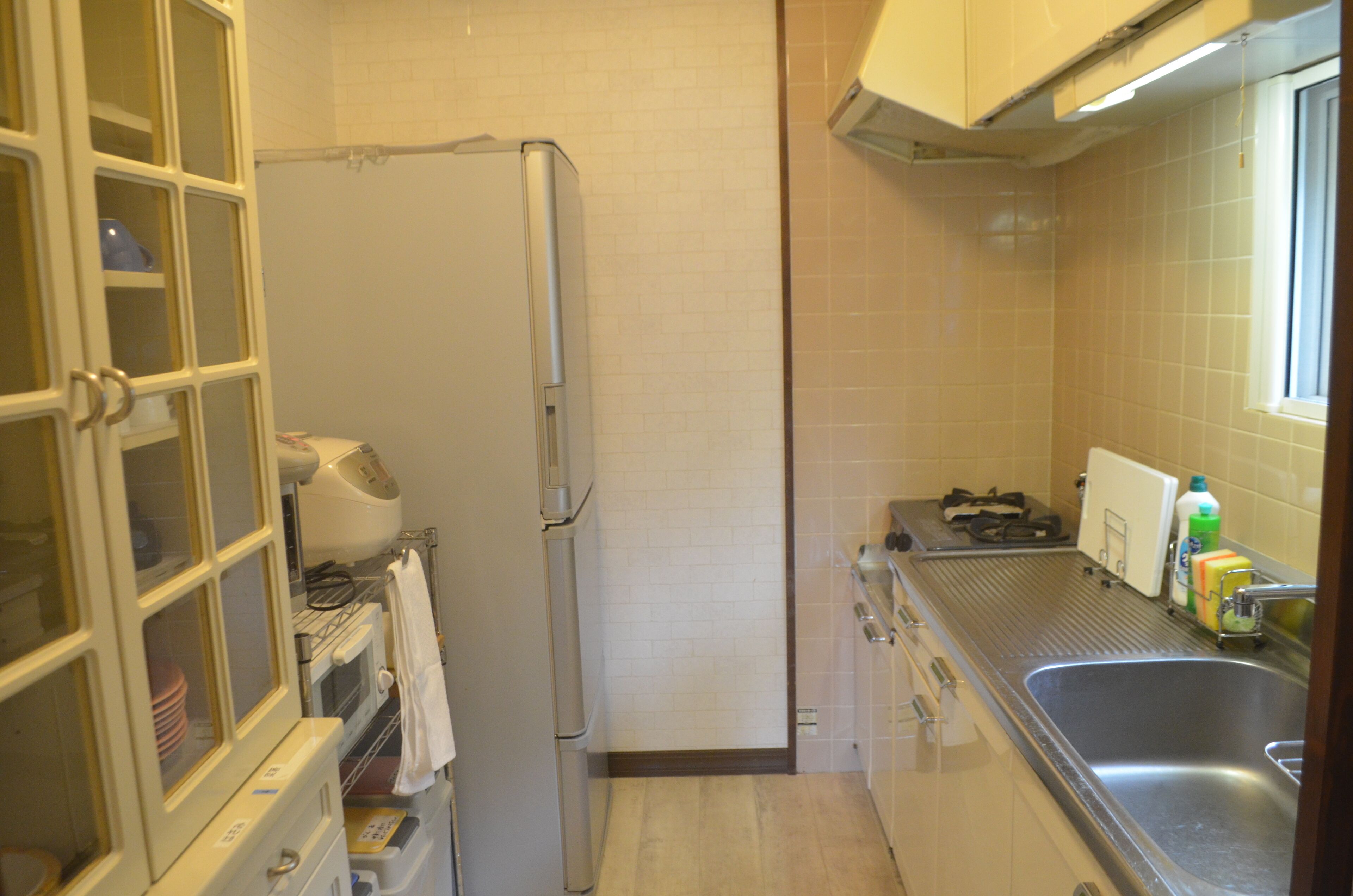 Una cocina compacta con refrigerador, lavamanos y ventana.