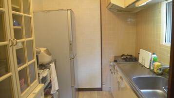 Una cocina compacta con refrigerador, lavamanos y ventana.