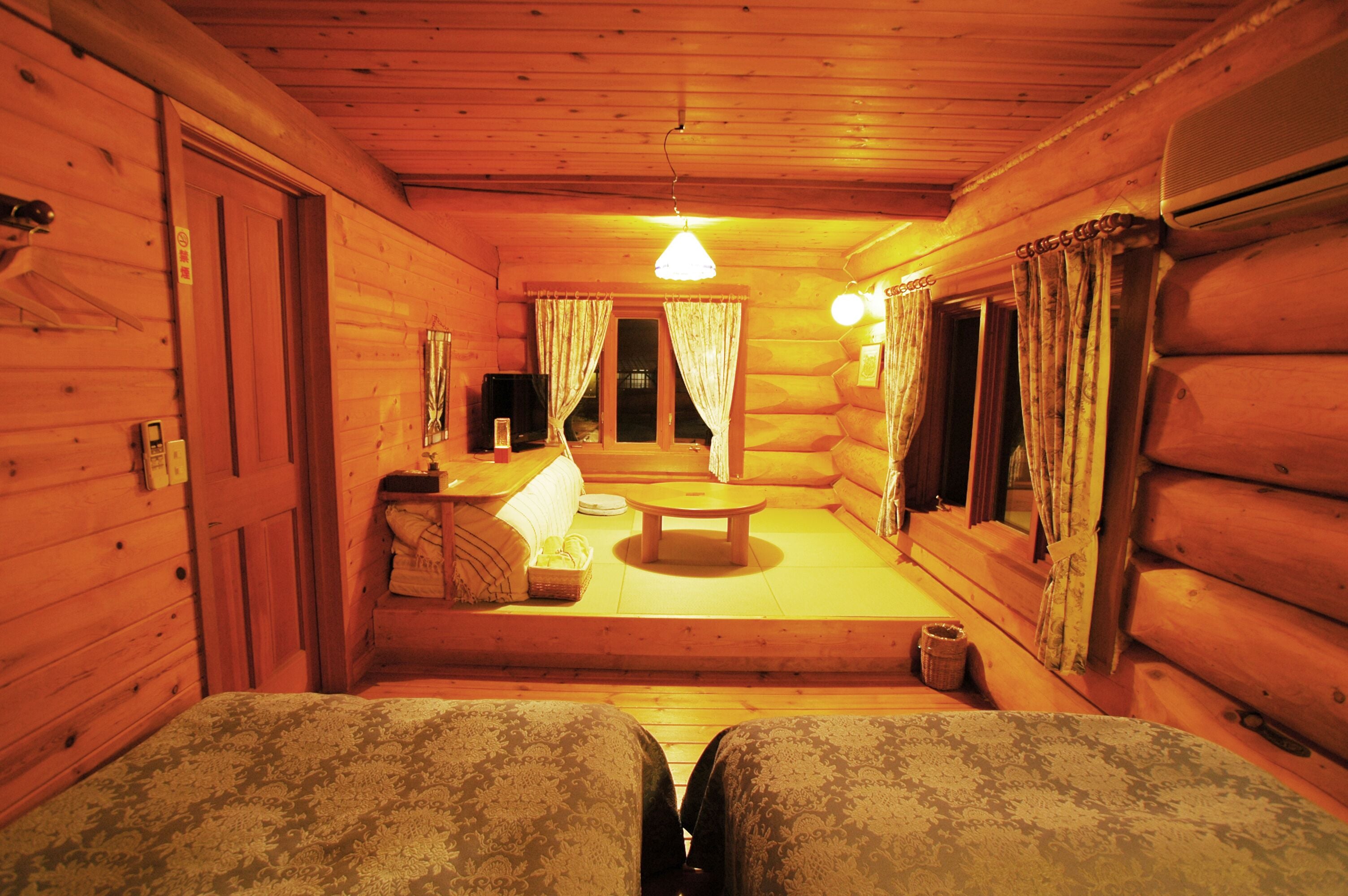 A cozy log cabin interior with a sofa set, a small table, and a window with curtains.