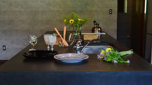 A modern kitchen with a dark countertop, a sink, a kettle, and a vase with flowers.