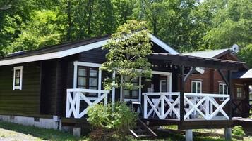 A cabin with a porch, a small tree, and a satellite dish.