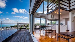 A modern kitchen with large windows, a wooden deck, and a view of the sea. - E-horizon Resort Condominium Yomitan (Yomitan)