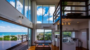 A modern kitchen with a view of the sea, a dining area with a wooden table, and a balcony with a railing. - E-horizon Resort Condominium Yomitan (Yomitan)