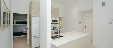 Una cocina moderna con una isla central, electrodomésticos integrados y un pequeño comedor.