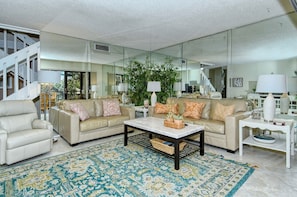 A spacious living room with a beige sofa set, a coffee table, and a patterned rug.