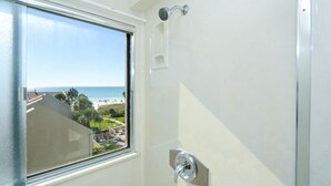 Ein Badezimmer mit einem großen Fenster und Blick auf Strand und Meer.