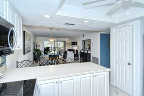 A modern kitchen with white cabinetry, a granite countertop, and a built-in stove. - Chinaberry 426- Beautifully updated and redecorated unit on the 2nd floor (Siesta Key)