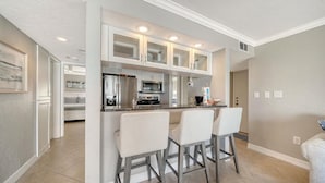 A modern kitchen with white cabinetry, a central island with bar stools, and a built-in oven.