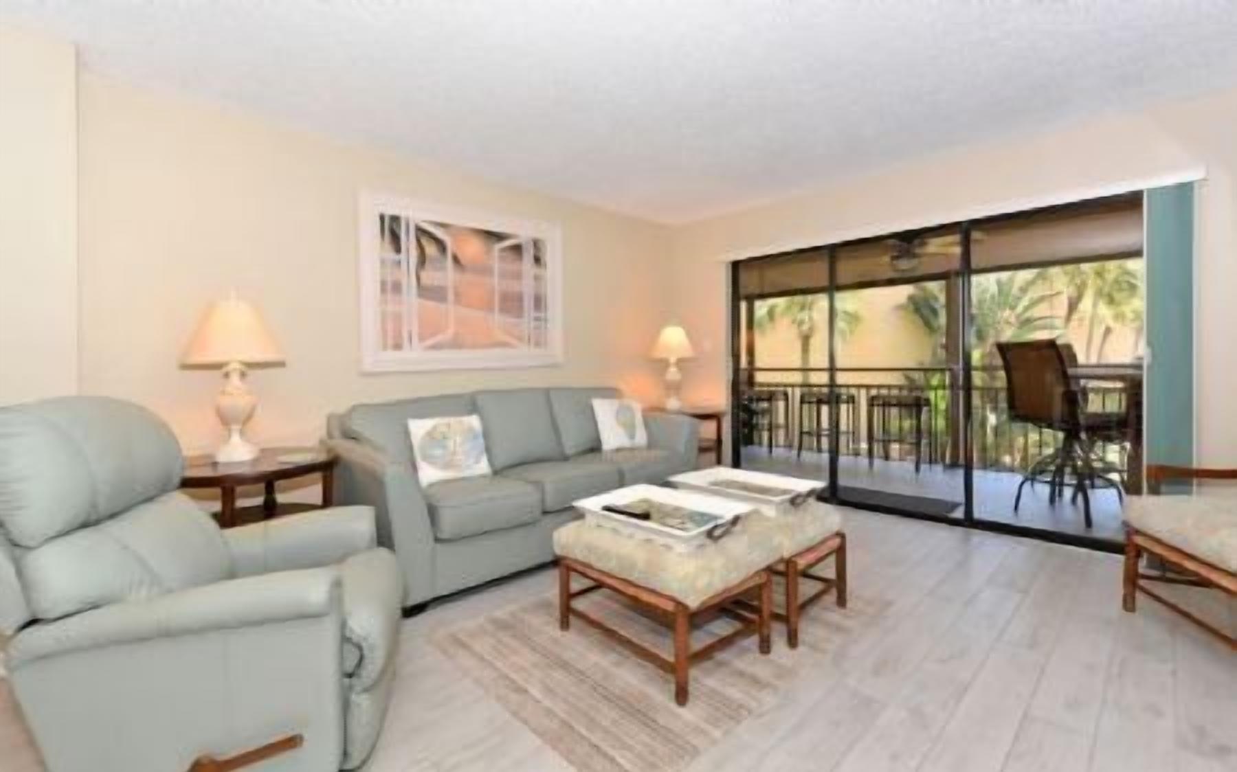 A living room with a sofa, armchair, coffee table, and a dining area with chairs and a table.