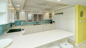 Eine moderne Küche mit weißen Schränken, einer blauen gefliesten Spritzschutzwand und einer weißen Arbeitsplatte.
