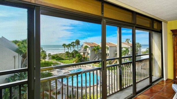 Ein Balkon mit Blick auf einen Swimmingpool und den Ozean.