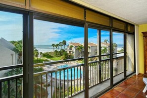 A balcony with a view of a swimming pool and ocean.