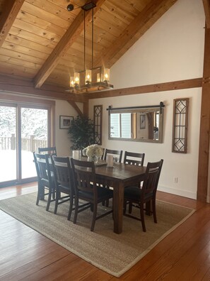 A dining room with a wooden table, six chairs, a chandelier, and a large mirror on the wall. - Beautiful Custom Built Timber Frame Home, Sleeps 11 (Wilmington)