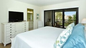 Une chambre à coucher avec un lit, un téléviseur posé sur une commode et un balcon avec vue.