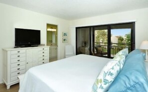 Une chambre à coucher avec un lit, un téléviseur posé sur une commode et un balcon avec vue.