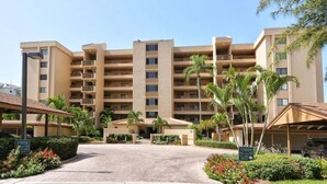 Un hôtel à plusieurs étages doté d’une cour intérieure, de palmiers et offrant une vue sur un ciel dégagé.