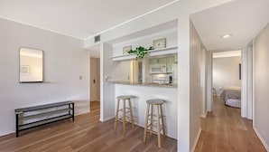 Een moderne keuken met een ingebouwde magnetron en oven, houten krukken en een bank.