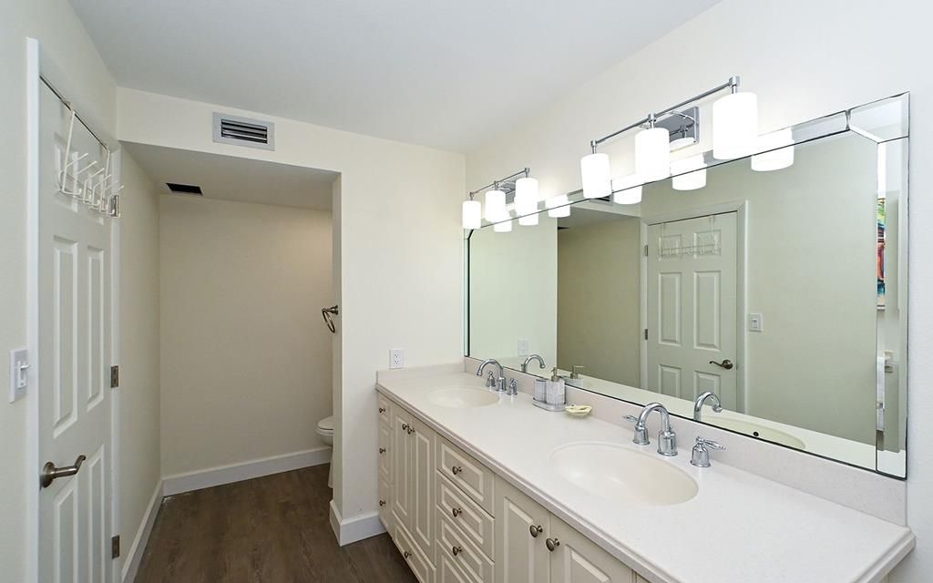 A bathroom with a double sink vanity, a large mirror, and a walk-in shower.