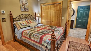 Ein Schlafzimmer mit einem großen Bett, einem Holzkopfende, einer Steudecke, einer Holztür und einem Flur, der in einen anderen Raum führt.