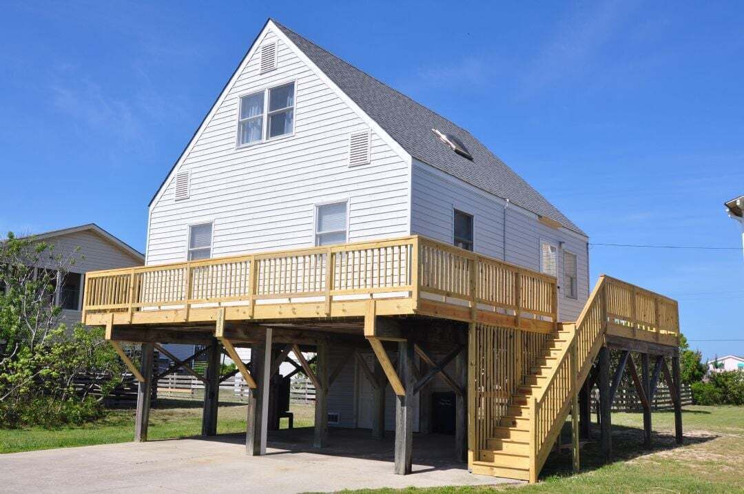 Een wit gebouw met een balkon en een houten trap.