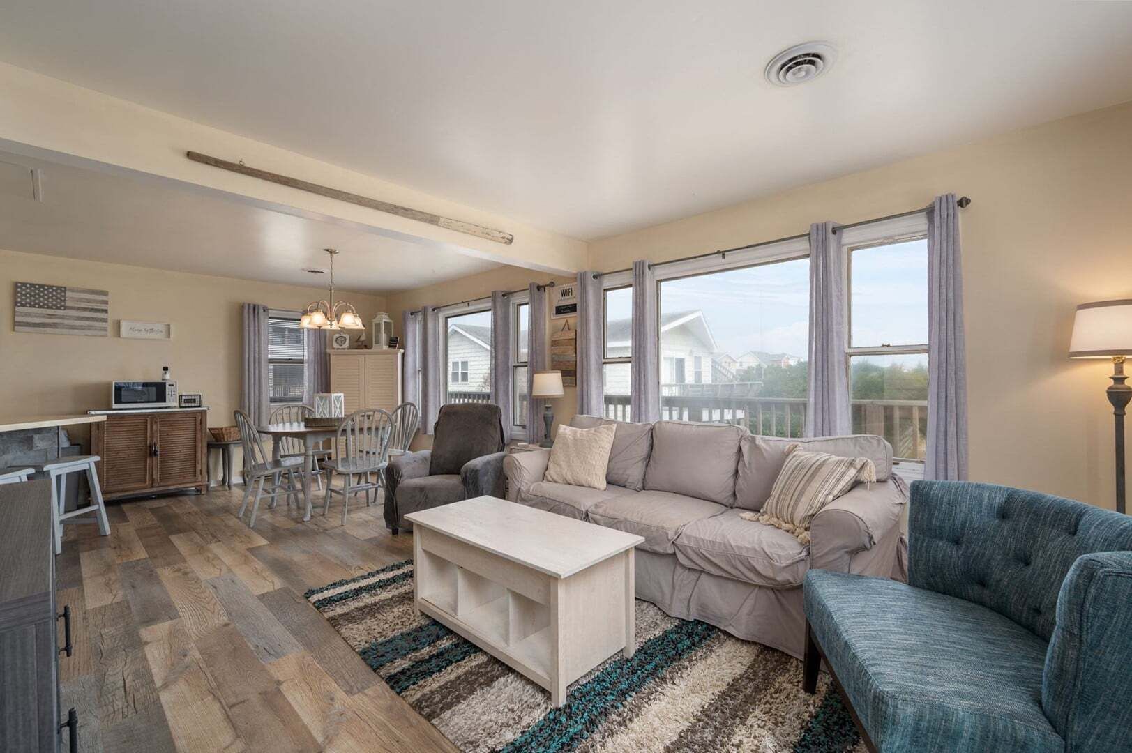 A living room with a sofa, armchair, dining table, and chairs.