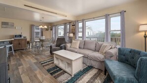 Una sala de estar con sofá, sillón, mesa de comedor y sillas.