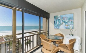 A balcony with wicker furniture, a painting, and a view of the beach. - Buttonwood 477- Spectacular Gulf of Mexico views from this seventh floor (Siesta Key)