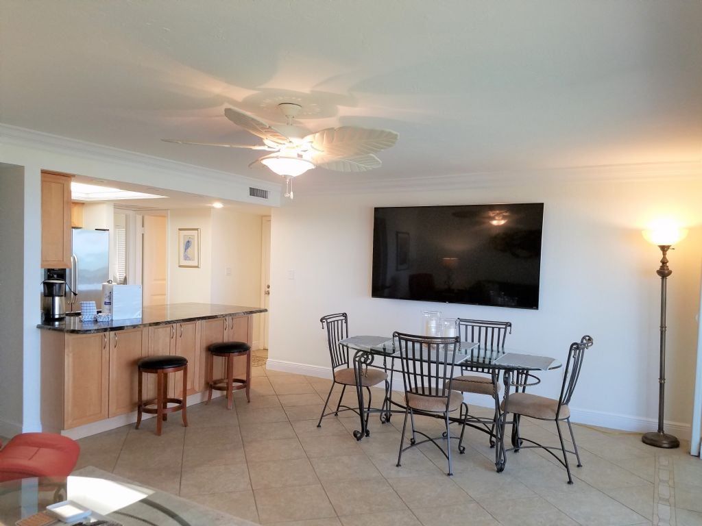 A modern kitchen with a bar area, dining table, and chairs.