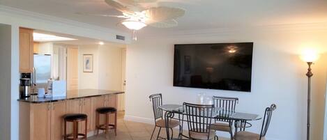 A modern kitchen with a bar area, dining table, and chairs.