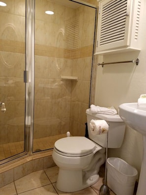 Une salle de bain comprenant une douche à parois de verre, des toilettes, un bidet et un lavabo.