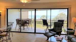 Une chambre dotée d’un ventilateur de plafond, d’un balcon avec une table et des chaises, et offrant une vue sur l’océan.
